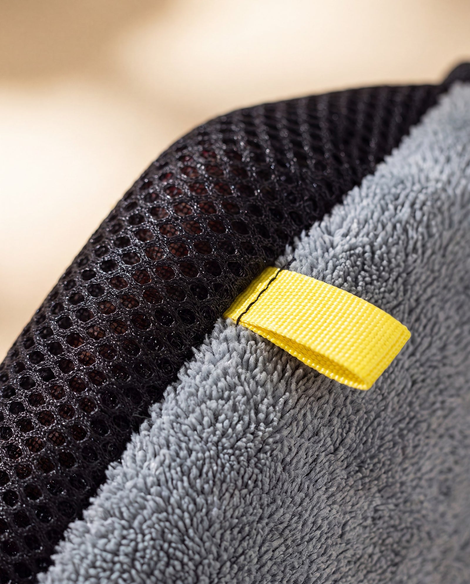 Macro detail of the Petting Glove fabric — black mesh to grey microfiber transition and yellow tab