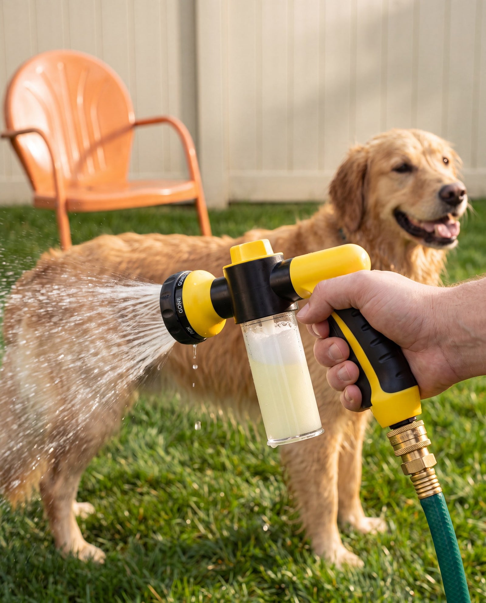 Hand holding the Reset Jet washing a golden retriever outdoors, foamy soap reservoir visible